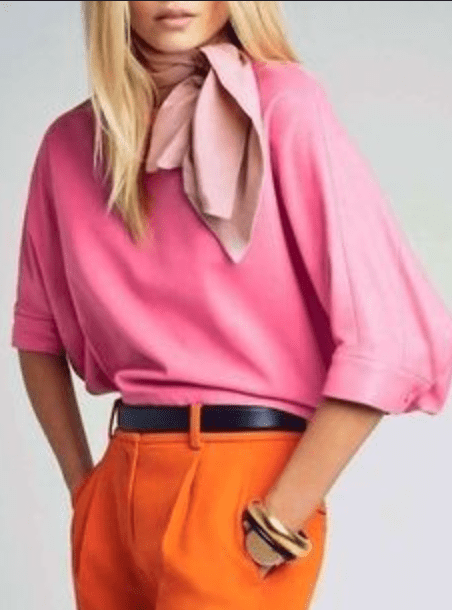 A woman wearing a pink top and orange pants