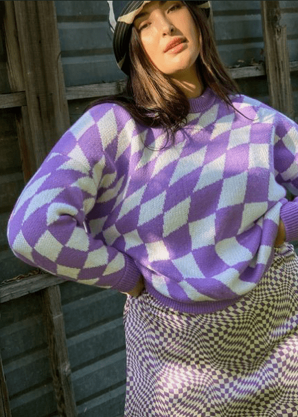 A woman wearing a cream and purple pattern top