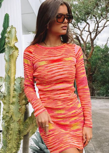 A woman wearing a colorful orange and yellow print dress
