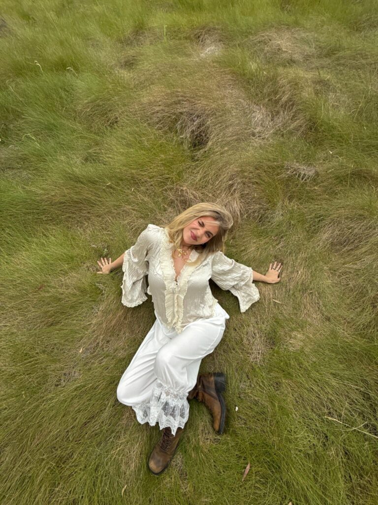 Sustainable Fashion Advocate Lexy Silverstein lays in a field of grass.